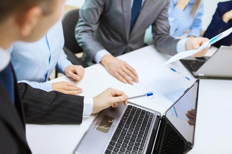 Group of employees collaborting over a computer